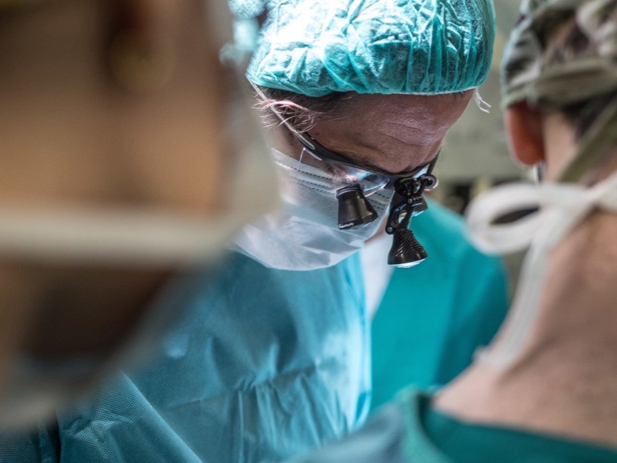 Surgeons at work in an operating room, shot close and observational with the nearest figure out of focus